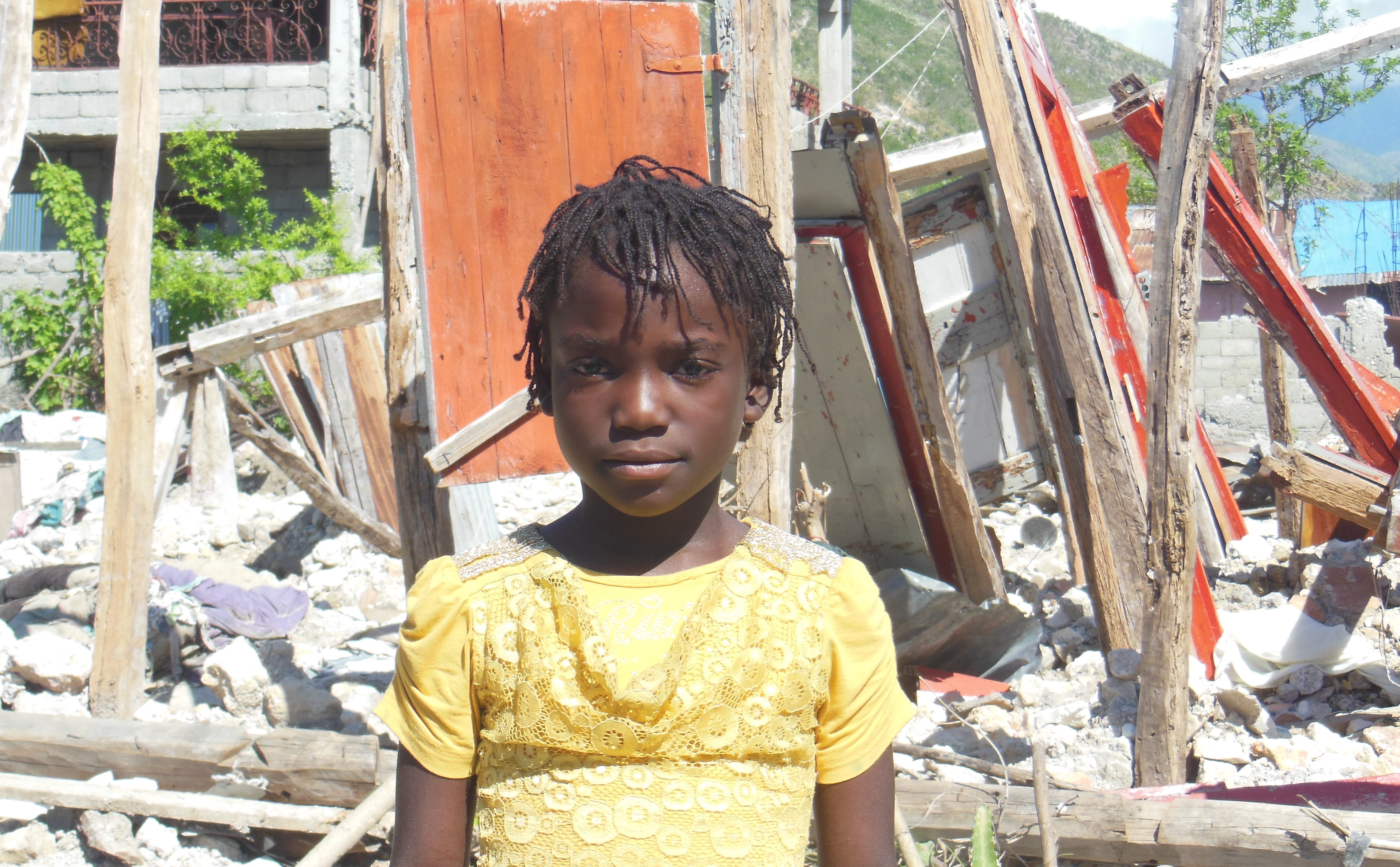 Ein Mädchen vor den Trümmern ihres Hauses in Haiti. (Quelle: Kindernothilfe-Partner)
